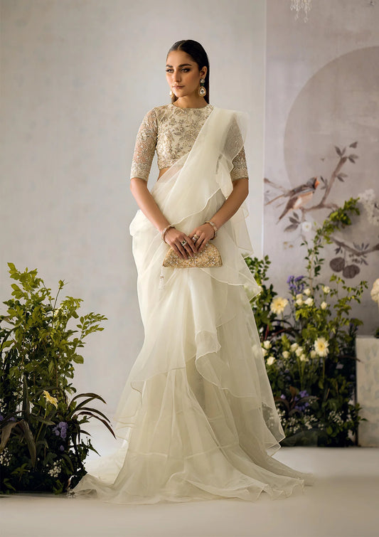 Pristine white organza saree with a dramatic ruffled hem, paired with an embroidered net blouse featuring light gold tilla, sequins, and delicate lace accents.