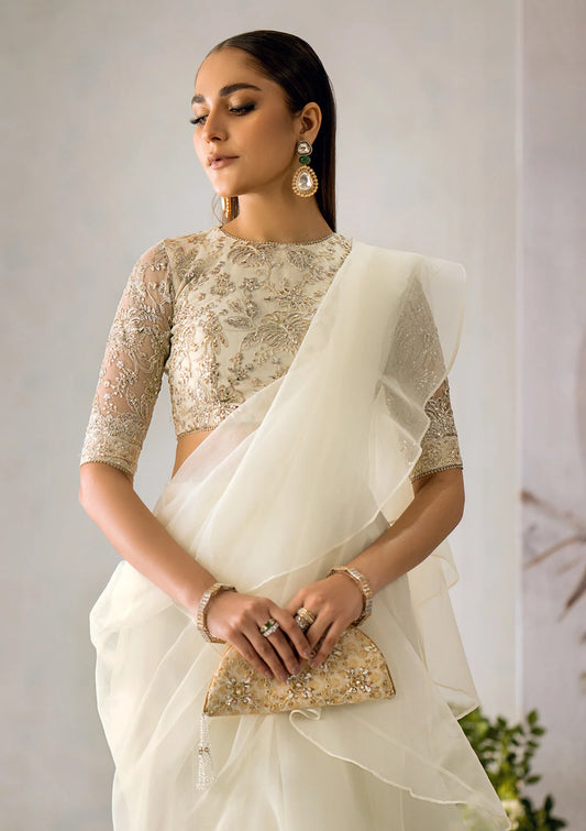 Pristine white organza saree with a dramatic ruffled hem, paired with an embroidered net blouse featuring light gold tilla, sequins, and delicate lace accents.