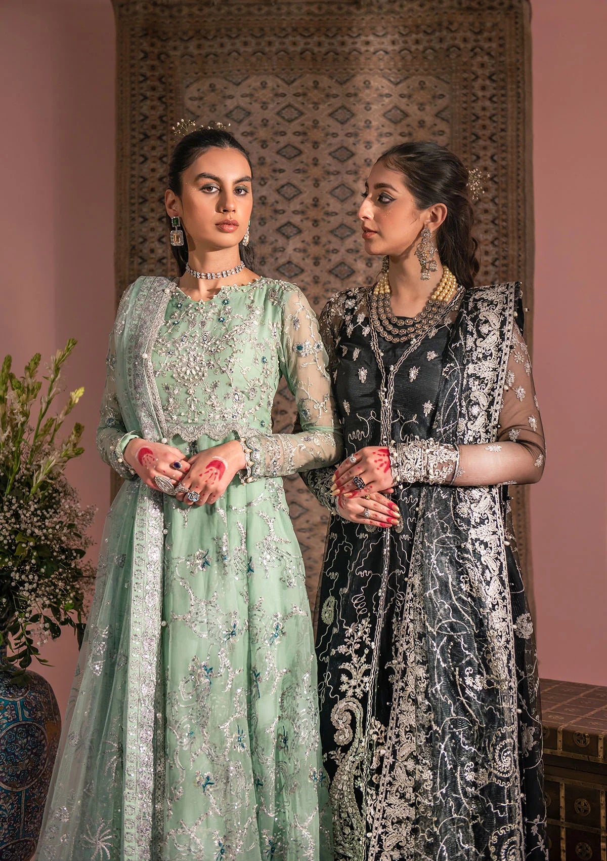 Timeless black net ensemble featuring Kashmiri paisley motifs, refined sequin and bead embellishments, organza borders, raw silk pants, and an embroidered net dupatta for elegant monochrome appeal.