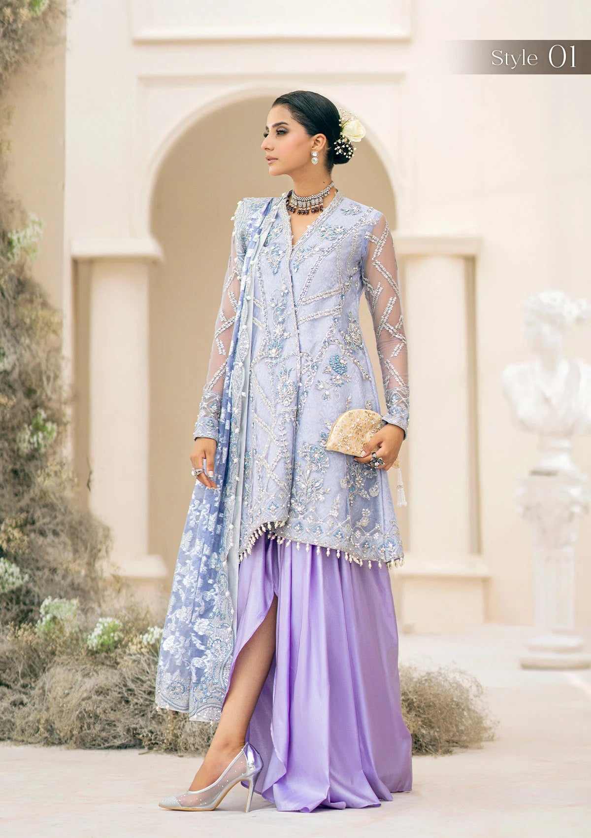 Exquisite lavender net ensemble featuring crystal and pearl embellishments, tilla-infused embroidery, masoori silk pants, and an organza jacquard dupatta. Styled as a short shirt with draped skirt or long shirt with sharara pants.