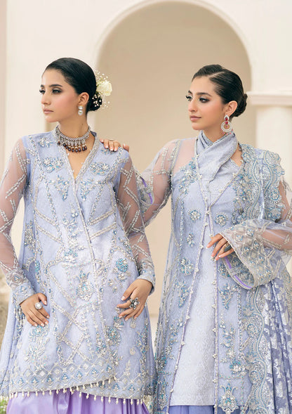 Exquisite lavender net ensemble featuring crystal and pearl embellishments, tilla-infused embroidery, masoori silk pants, and an organza jacquard dupatta. Styled as a short shirt with draped skirt or long shirt with sharara pants.