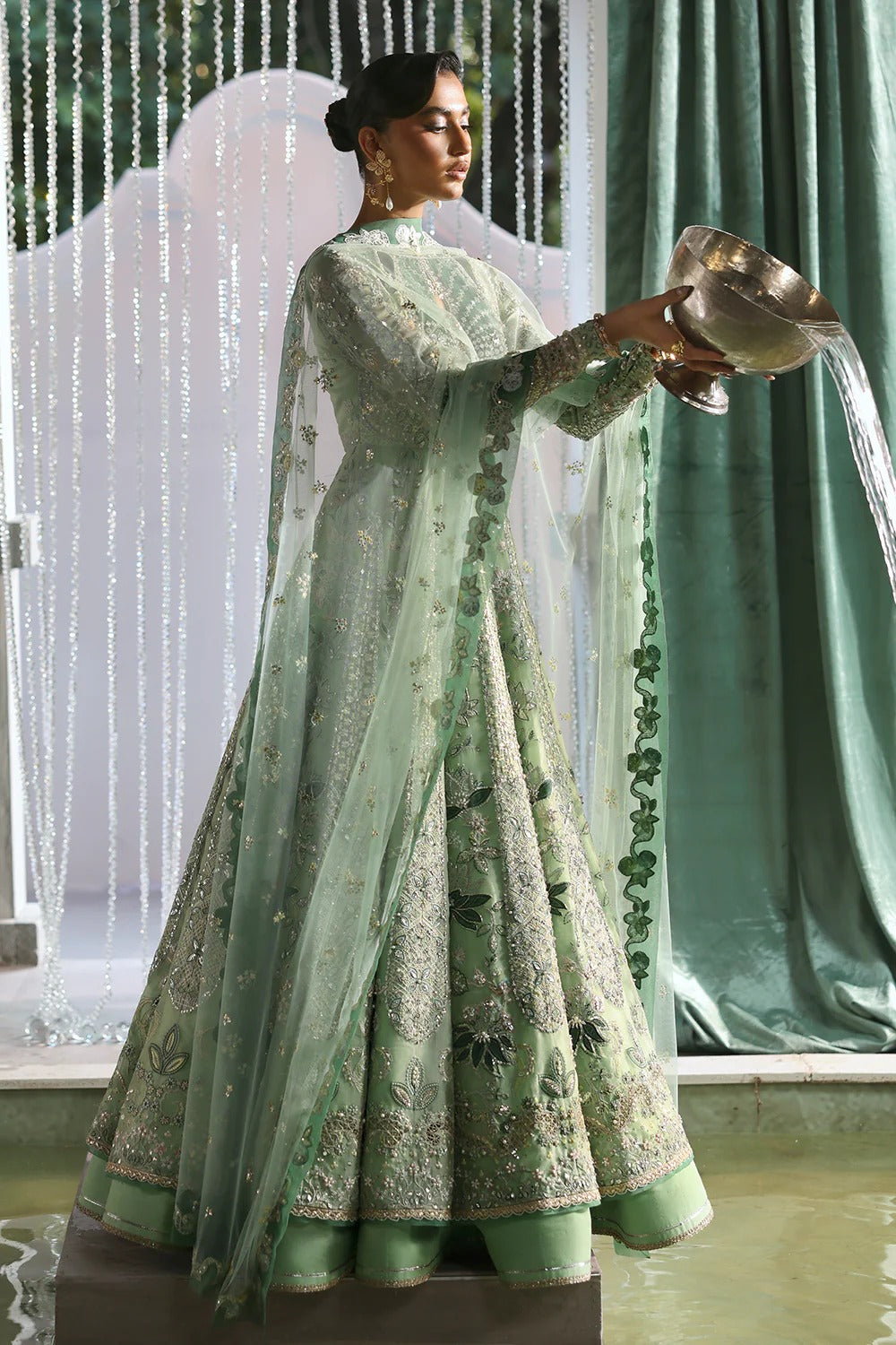 Elegant mint green silk suit featuring embroidered organza panels, velvet neck patch, net dupatta, and silk trousers. 