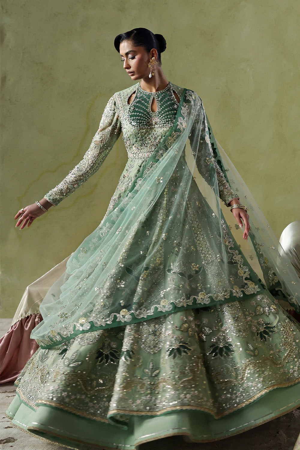 Elegant mint green silk suit featuring embroidered organza panels, velvet neck patch, net dupatta, and silk trousers. 