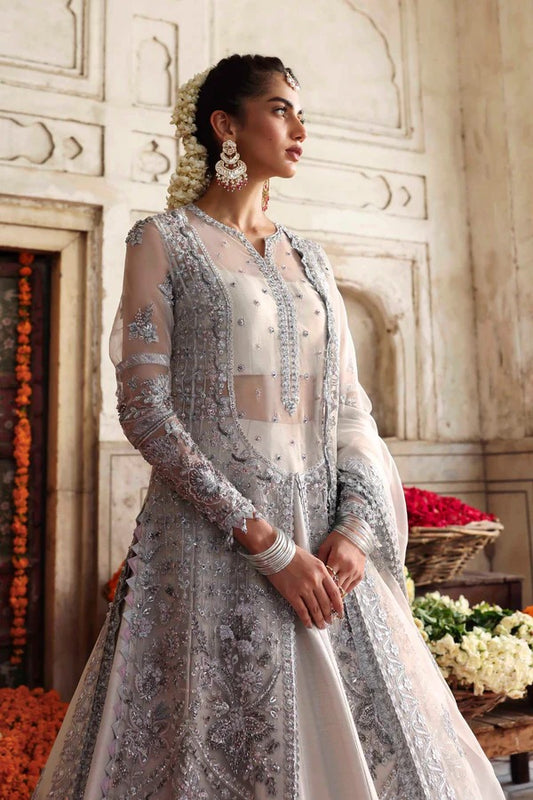 An elegant organza ensemble featuring hand-embellished panels, neckline, and sleeves. Paired with an embroidered dupatta and raw silk lehenga for a regal look.