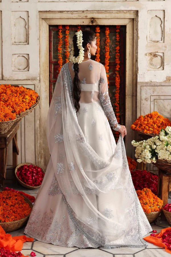 An elegant organza ensemble featuring hand-embellished panels, neckline, and sleeves. Paired with an embroidered dupatta and raw silk lehenga for a regal look.