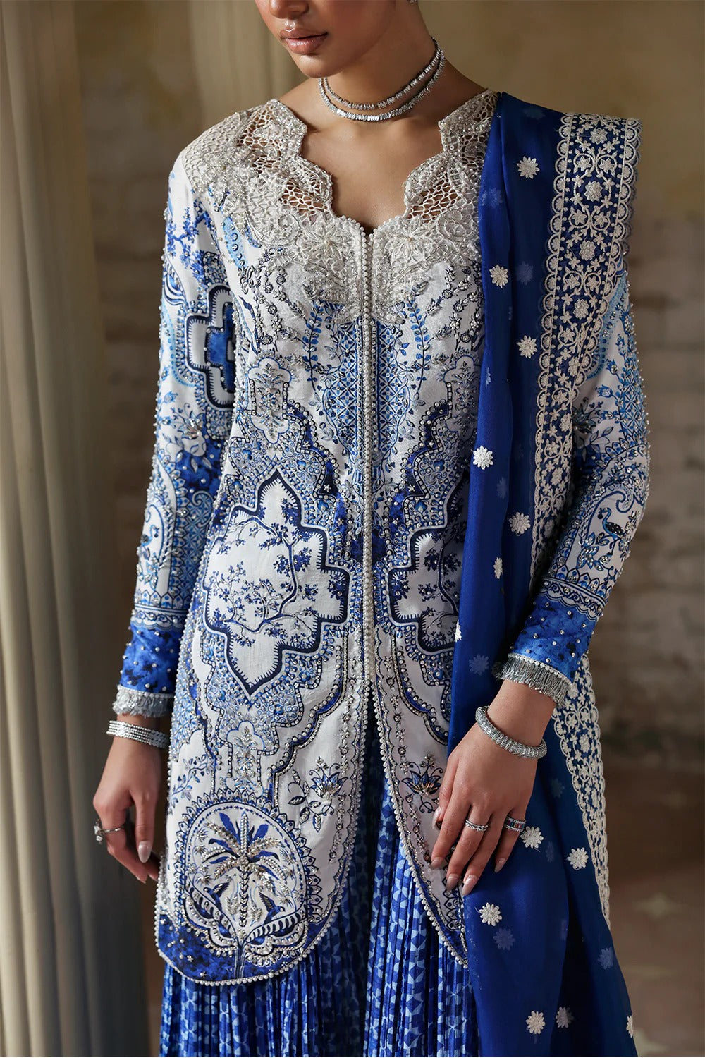 Elegant white blue printed silk suit with hand-embellished panels, embroidered dupatta,&   crushed sharara. Perfect for weddings, festive, and formal occasions.