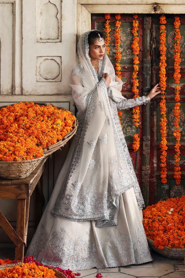 An elegant organza ensemble featuring hand-embellished panels, neckline, and sleeves. Paired with an embroidered dupatta and raw silk lehenga for a regal look.