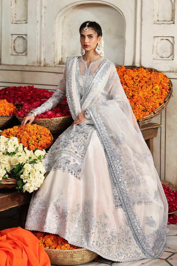 An elegant organza ensemble featuring hand-embellished panels, neckline, and sleeves. Paired with an embroidered dupatta and raw silk lehenga for a regal look.