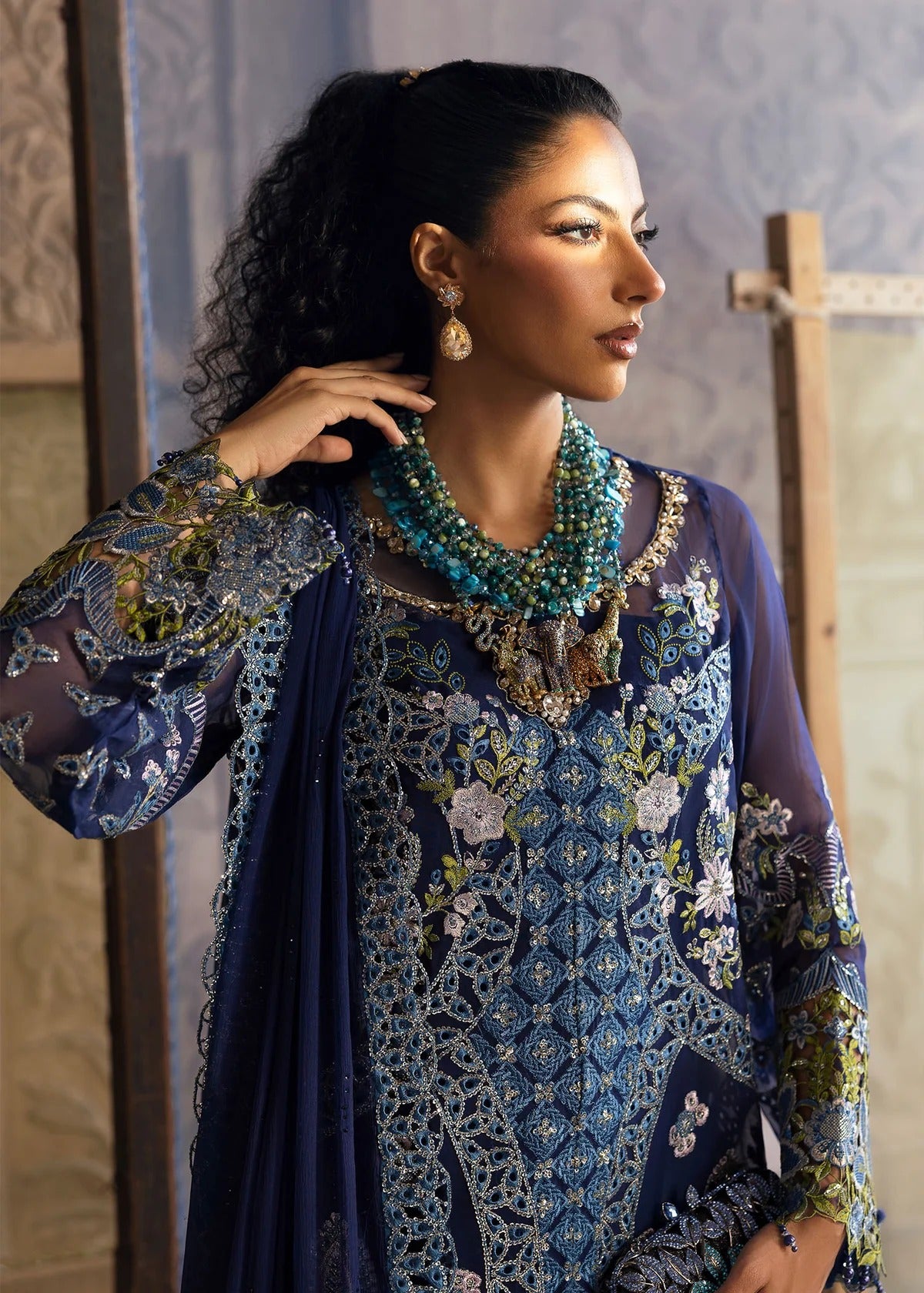 Stunning chiffon embroidered suit with hand-embellished neckline, cutwork motifs, diamante dupatta, and printed raw silk trouser for festive elegance.