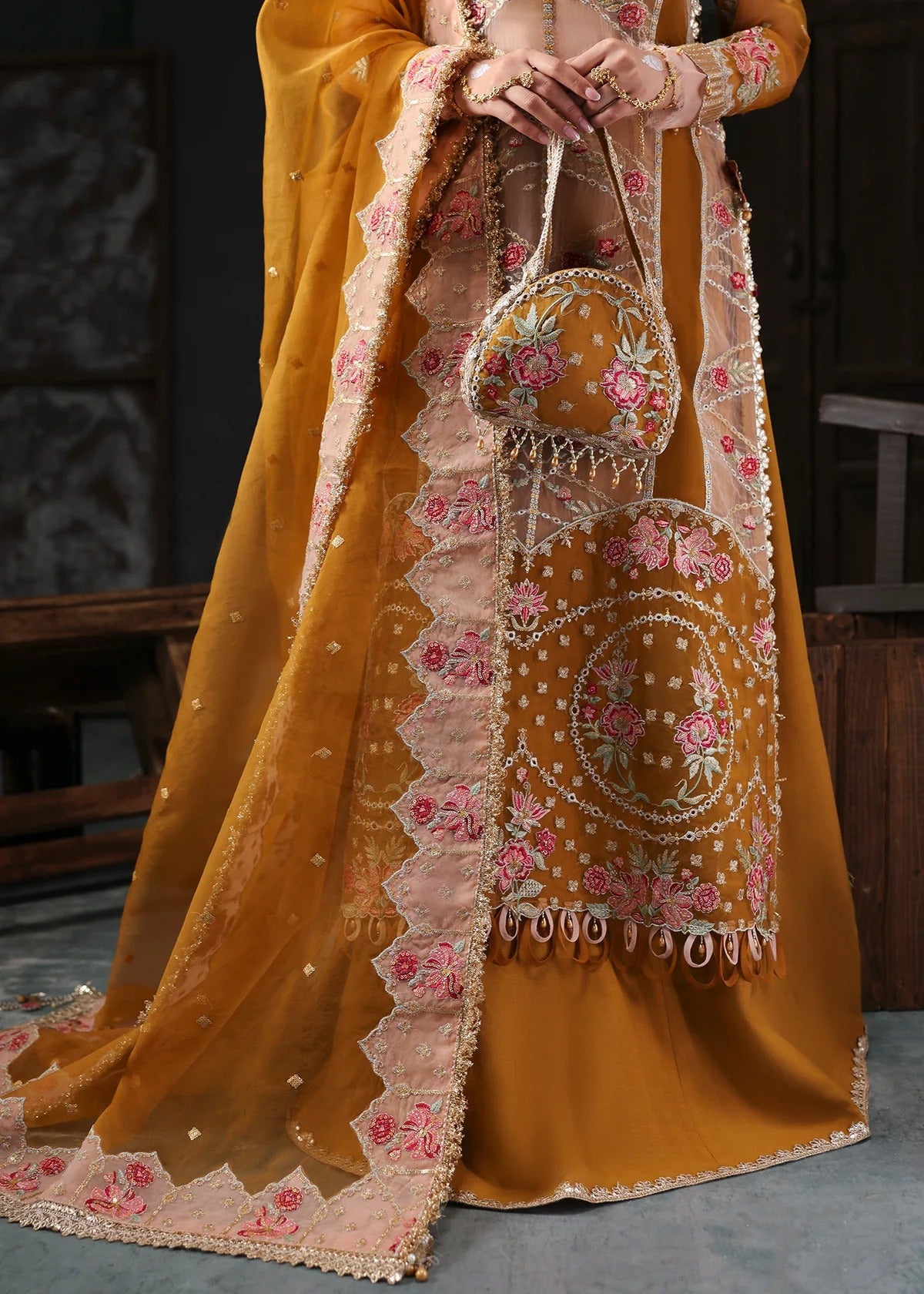 Chic mustard organza suit with applique front, embroidered neckline, dupatta with 4-side border, and raw silk trouser — perfect for festive wear.
