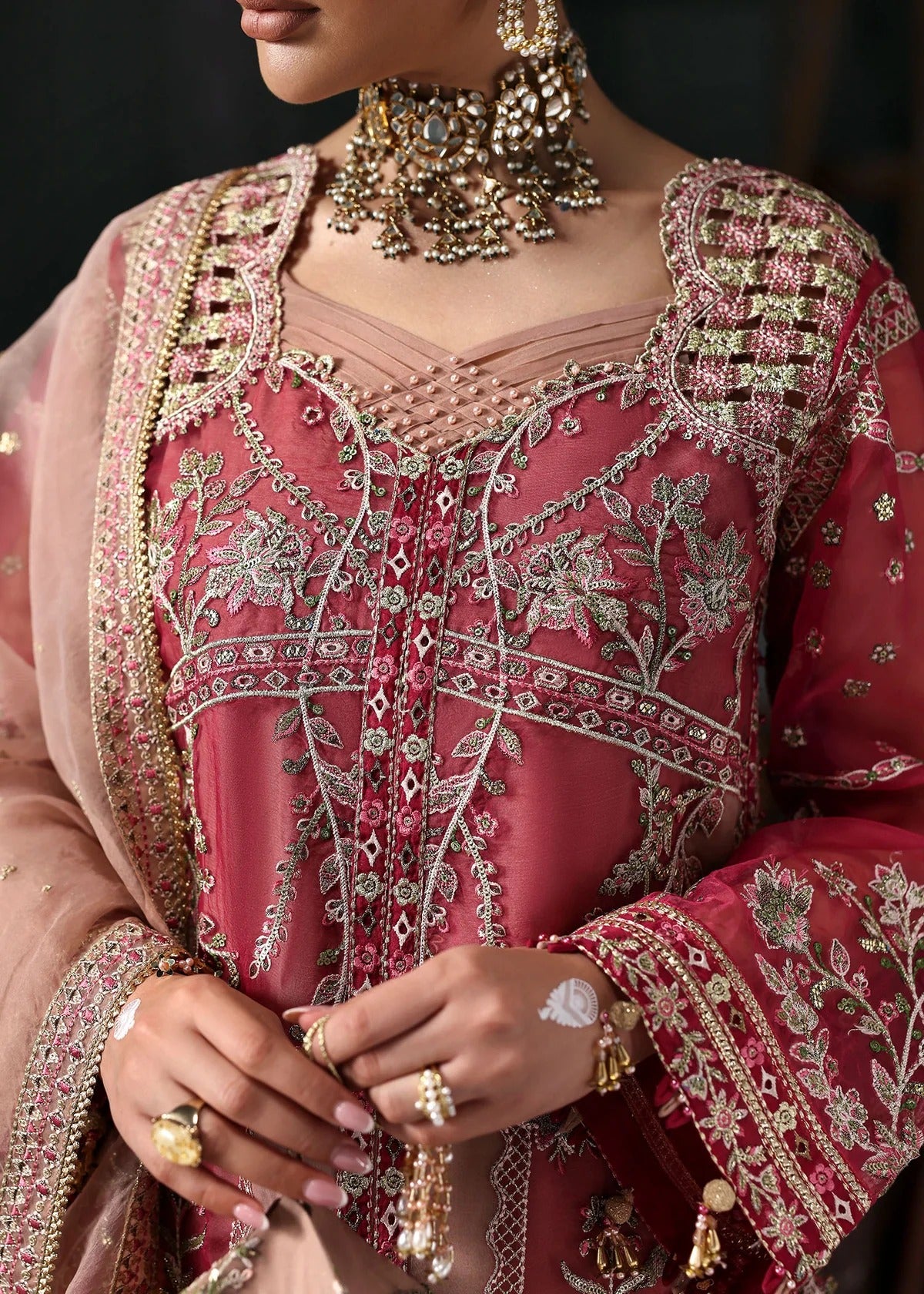 Chic rose pink organza suit with applique panels, cutwork neckline, embroidered dupatta, raw silk trouser, and elegant borders for a timeless festive look.