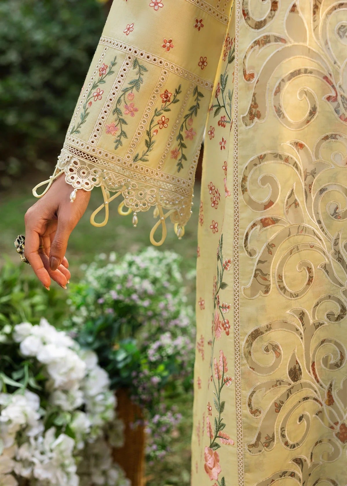 Shop this yellow embroidered lawn suit with chikan-kari sleeves, organza borders, woven net dupatta, and cotton trouser for an elegant summer look.