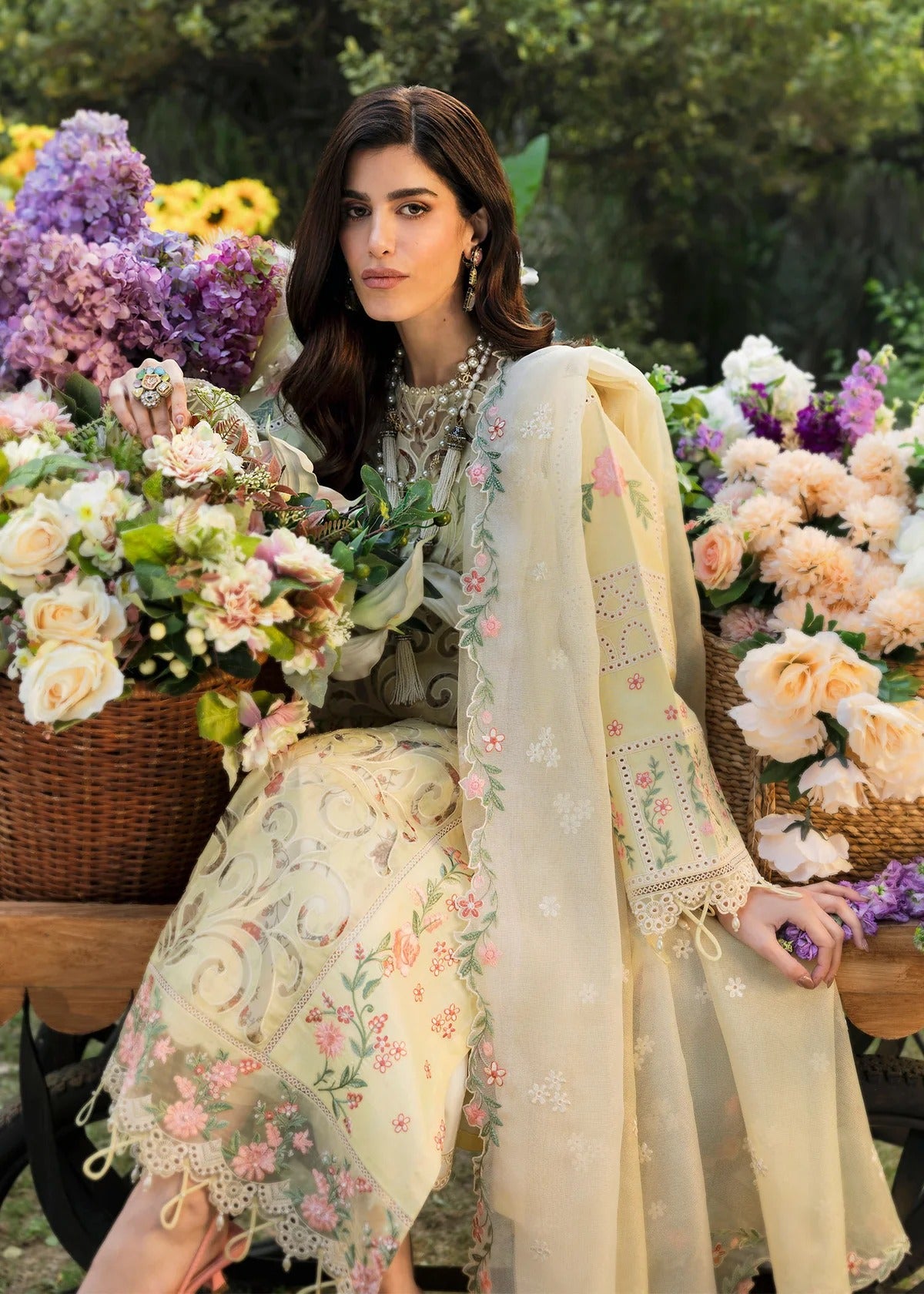 Shop this yellow embroidered lawn suit with chikan-kari sleeves, organza borders, woven net dupatta, and cotton trouser for an elegant summer look.