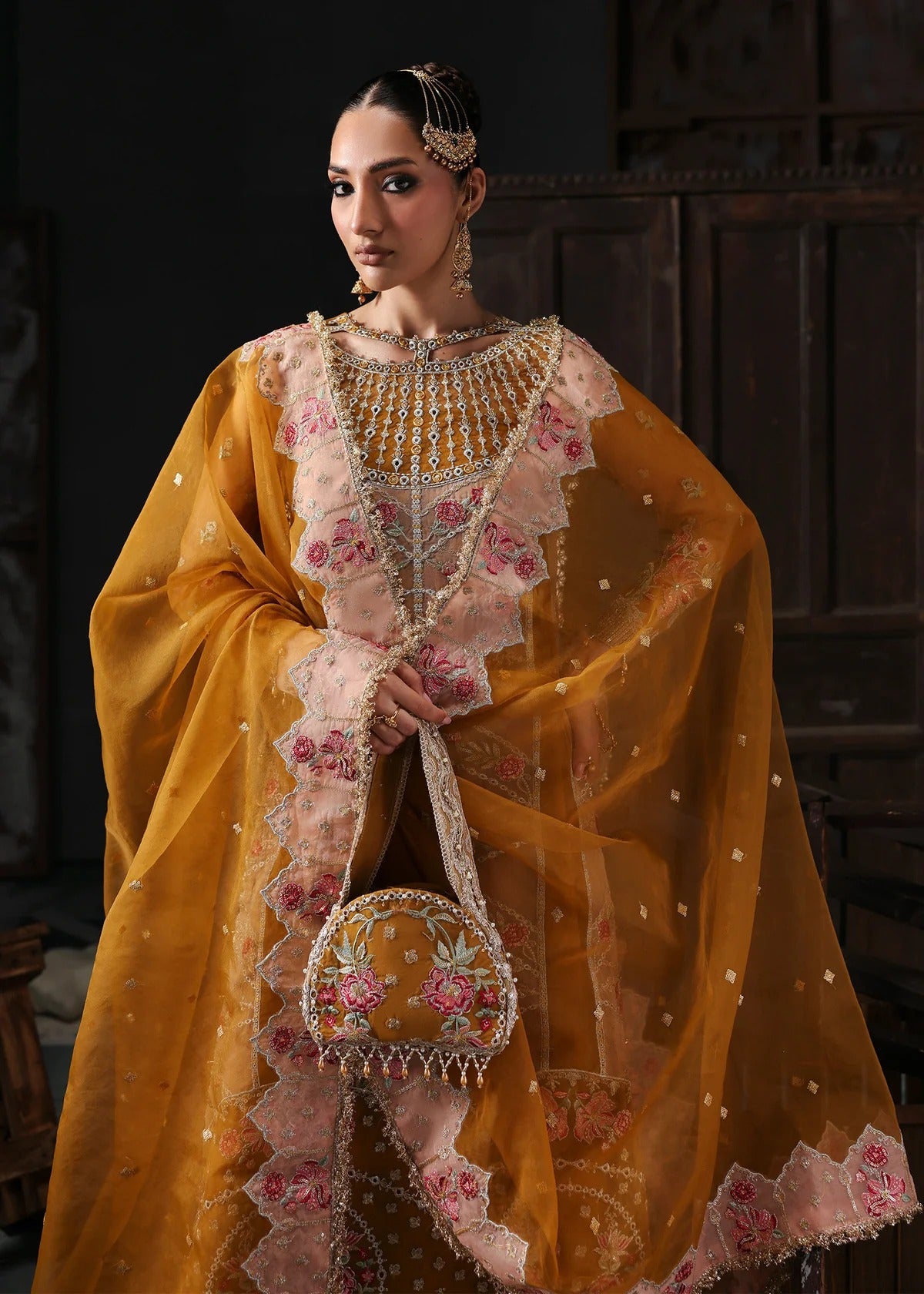 Chic mustard organza suit with applique front, embroidered neckline, dupatta with 4-side border, and raw silk trouser — perfect for festive wear.