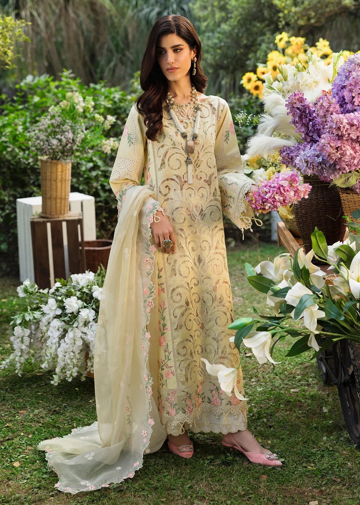 Shop this yellow embroidered lawn suit with chikan-kari sleeves, organza borders, woven net dupatta, and cotton trouser for an elegant summer look.