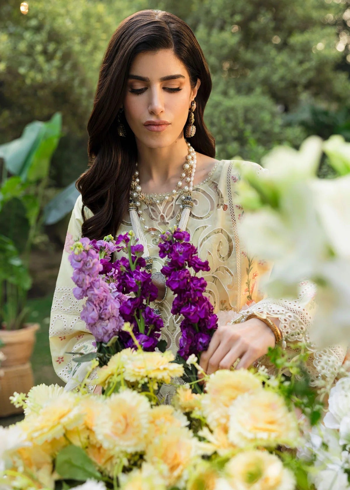 Shop this yellow embroidered lawn suit with chikan-kari sleeves, organza borders, woven net dupatta, and cotton trouser for an elegant summer look.