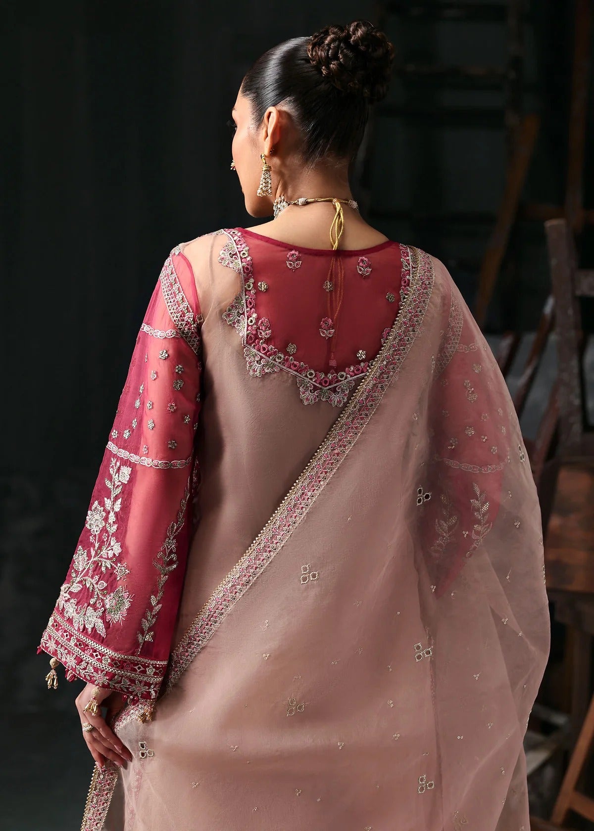 Chic rose pink organza suit with applique panels, cutwork neckline, embroidered dupatta, raw silk trouser, and elegant borders for a timeless festive look.