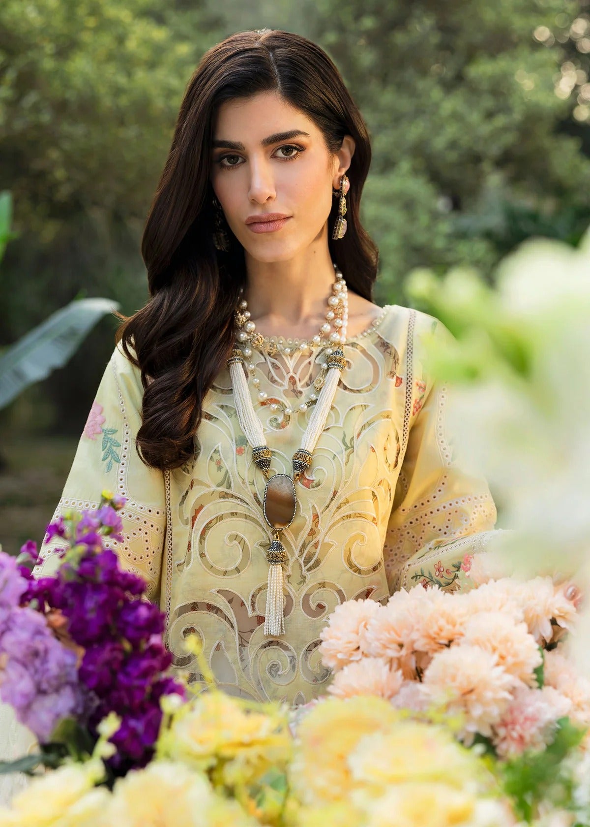 Shop this yellow embroidered lawn suit with chikan-kari sleeves, organza borders, woven net dupatta, and cotton trouser for an elegant summer look.