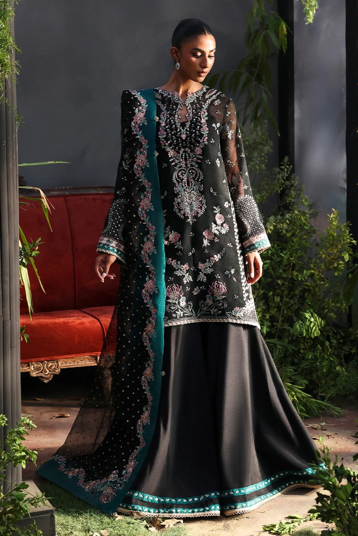 Stunning black khaadi net suit with embroidered panels, green & pink borders, block-printed organza dupatta, and raw silk trouser.