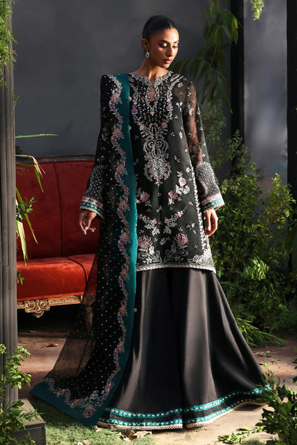 Stunning black khaadi net suit with embroidered panels, green & pink borders, block-printed organza dupatta, and raw silk trouser.
