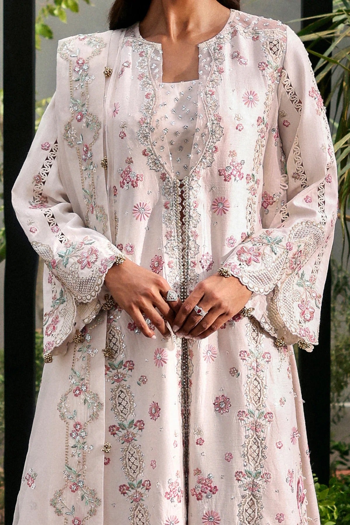 Elegant white raw silk suit featuring embroidered panels, organza borders, & a delicately embroidered dupatta with pallu  perfect for timeless festive elegance.