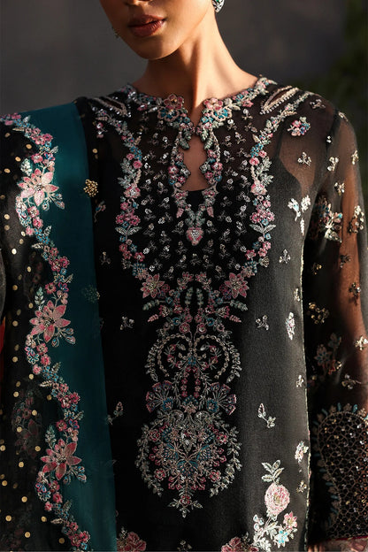 Stunning black khaadi net suit with embroidered panels, green & pink borders, block-printed organza dupatta, and raw silk trouser.