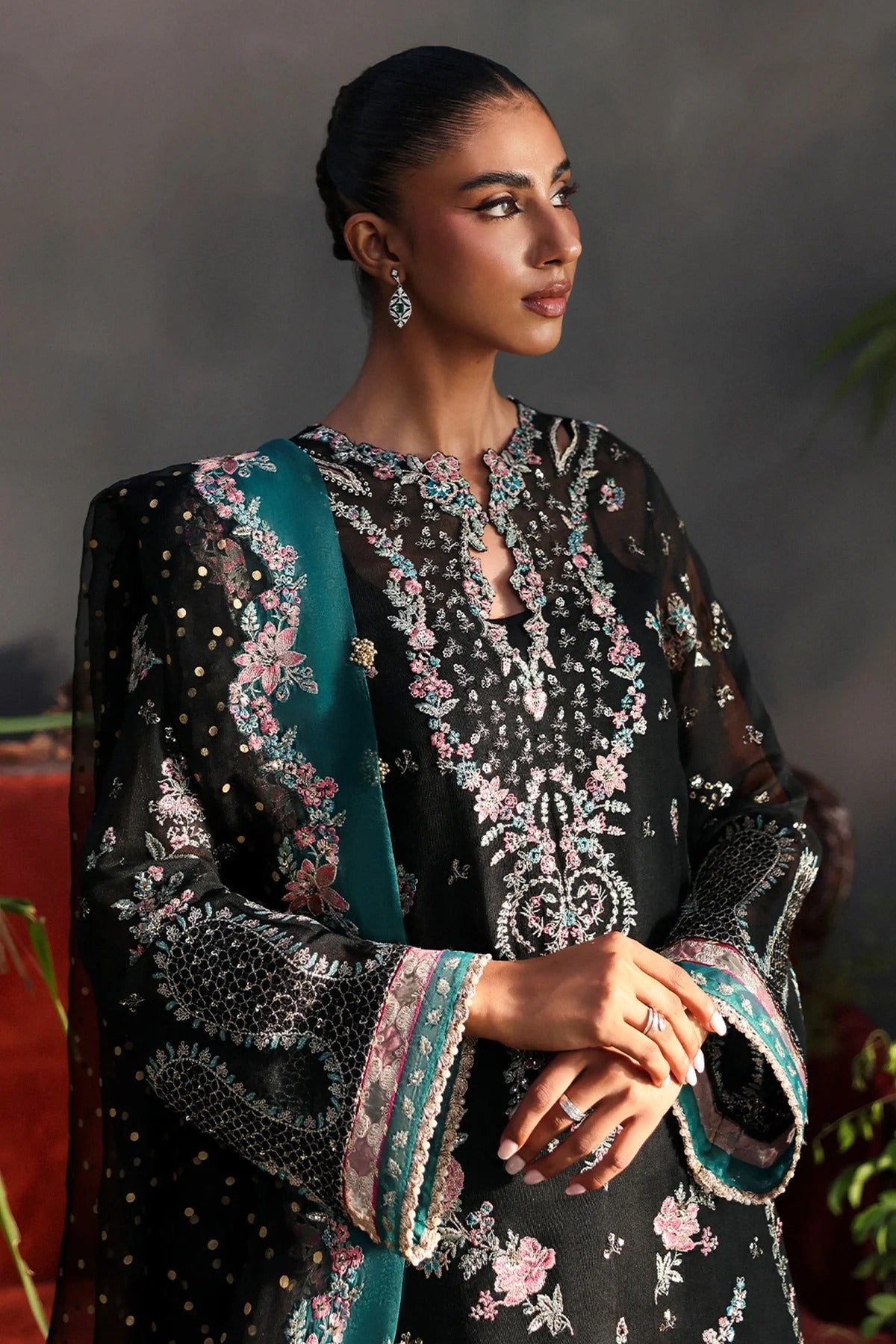 Stunning black khaadi net suit with embroidered panels, green & pink borders, block-printed organza dupatta, and raw silk trouser.