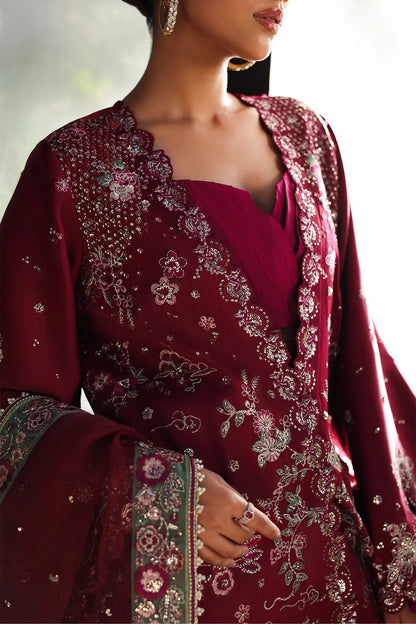 Striking cherry raw silk suit with embroidered panels, green organza dupatta border, and matching trouser for a bold festive look.