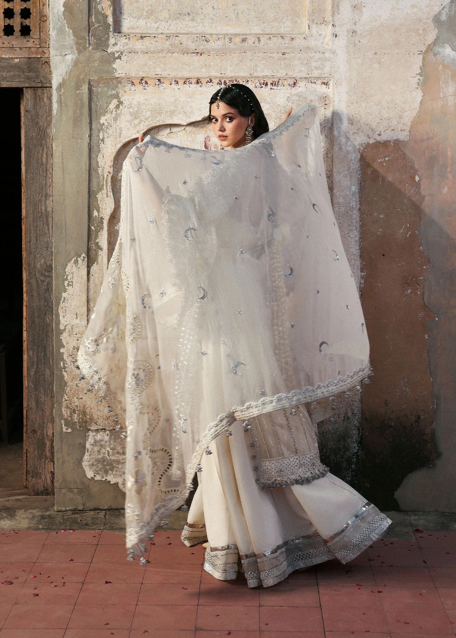 Elegant ivory organza shirt with sequin embroidery, silk sharara, and chiffon dupatta. Unstitched luxury outfit exuding timeless grace and sophistication.