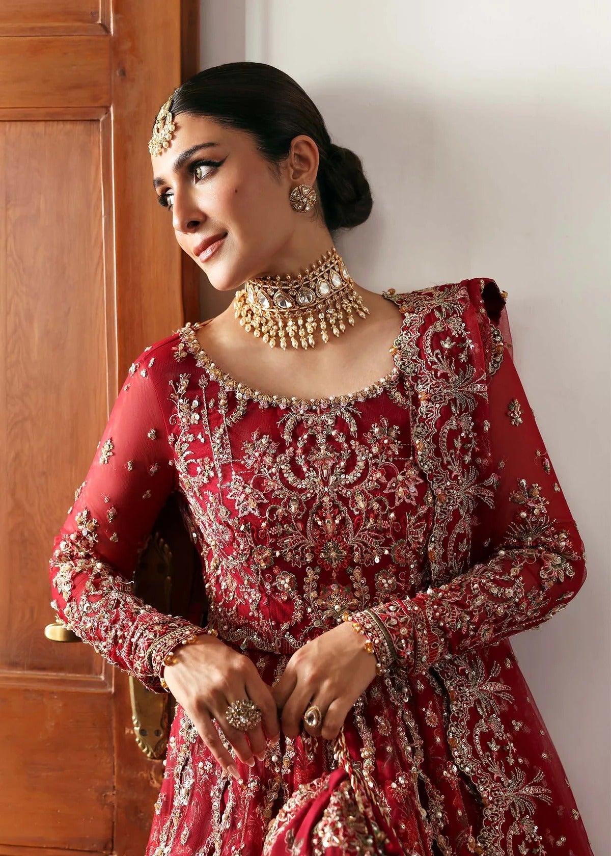 Regal crimson lehenga with hand-embellished panels, ornate borders, embroidered dupatta, and net body—perfect for festive and wedding elegance.