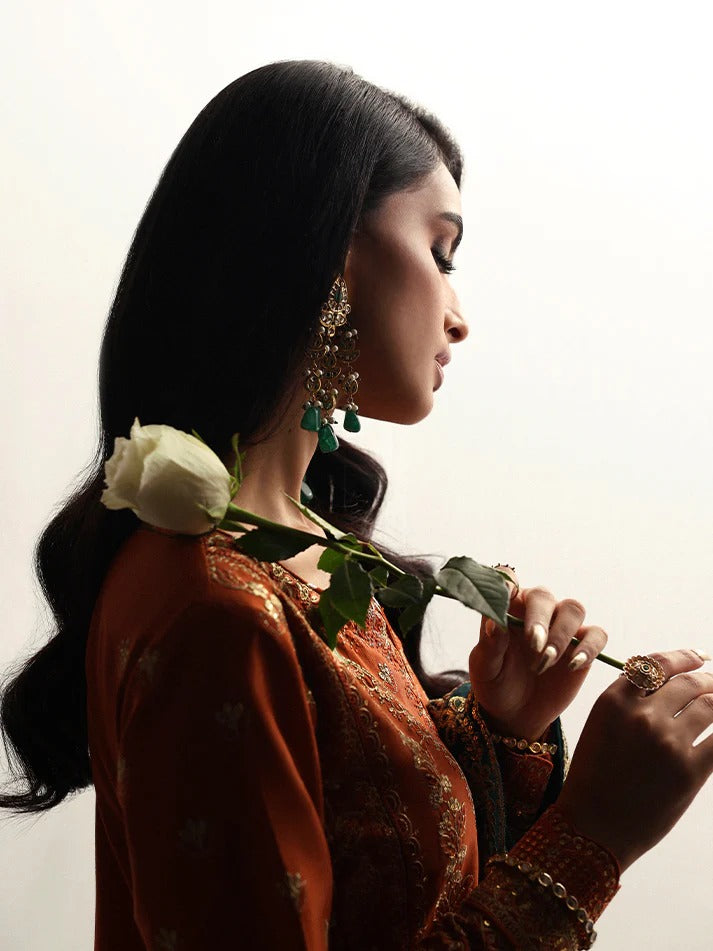 Grace your wardrobe with this embroidered and sequined raw silk outfit featuring detailed panels, chiffon dupatta with organza border, and dyed silk trousers.