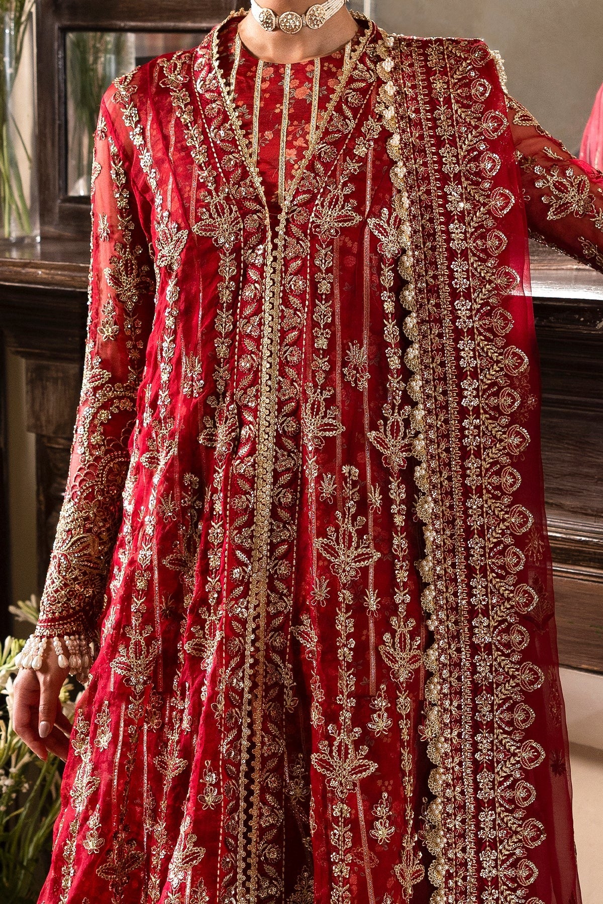 Striking red organza outfit with rich embroidery, dupatta, printed inner shirt, and embroidered trousers. A bold choice for weddings or festive events.