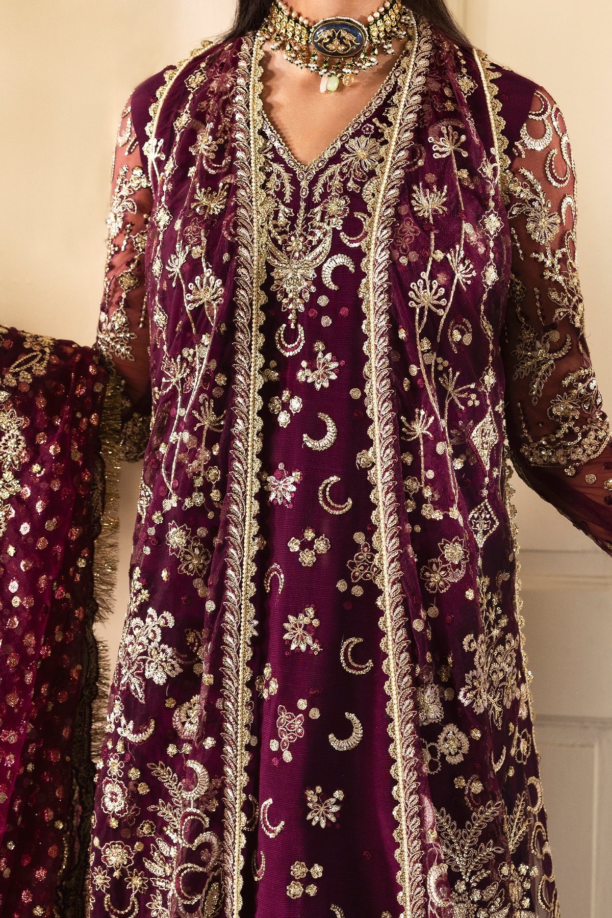Luxurious plum ensemble featuring raw silk and net embroidery, detailed dupatta borders, and dyed trousers. A perfect pick for festive and formal wear.
