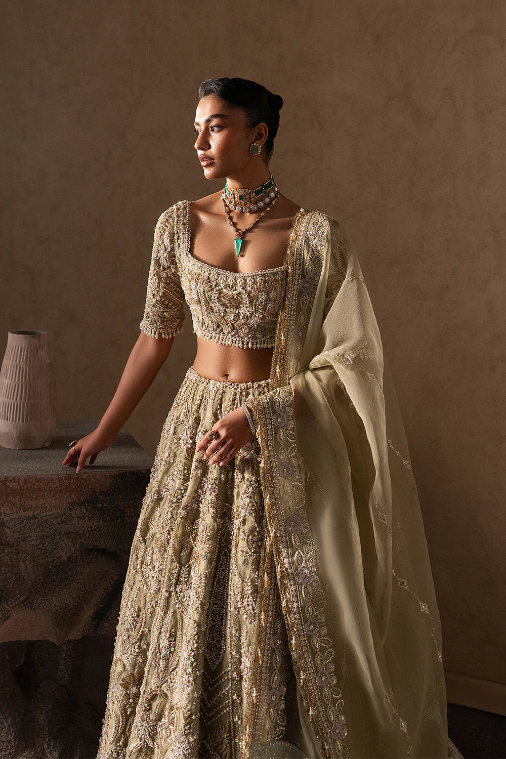 Elegant pastel gold bridal lehenga with intricate hand embellishment, paisley and floral motifs. Paired with a sheer dupatta for a timeless look.