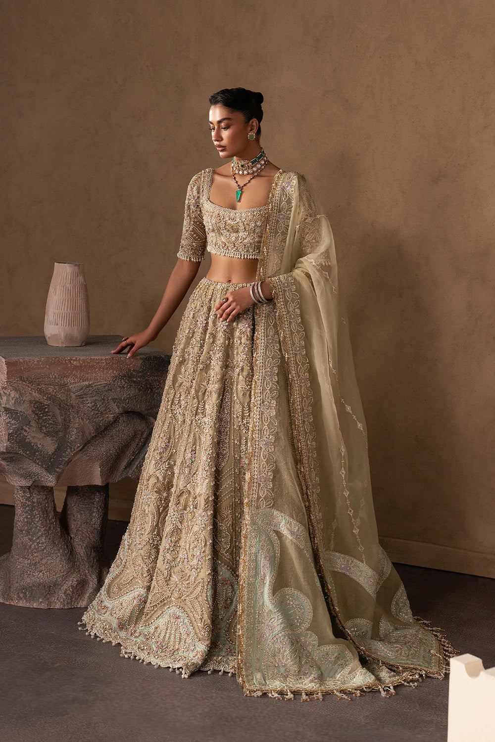 Elegant pastel gold bridal lehenga with intricate hand embellishment, paisley and floral motifs. Paired with a sheer dupatta for a timeless look.