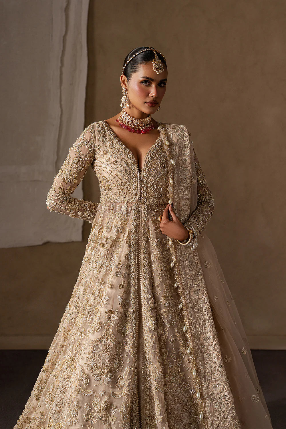 Majestic champagne bridal lehenga with hand embellishment and antique gold embroidery. Features ornate motifs, flowing skirt and elegant dupatta.
