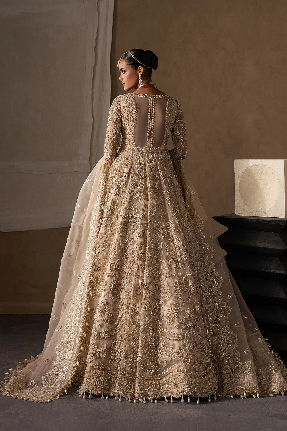 Majestic champagne bridal lehenga with hand embellishment and antique gold embroidery. Features ornate motifs, flowing skirt and elegant dupatta.