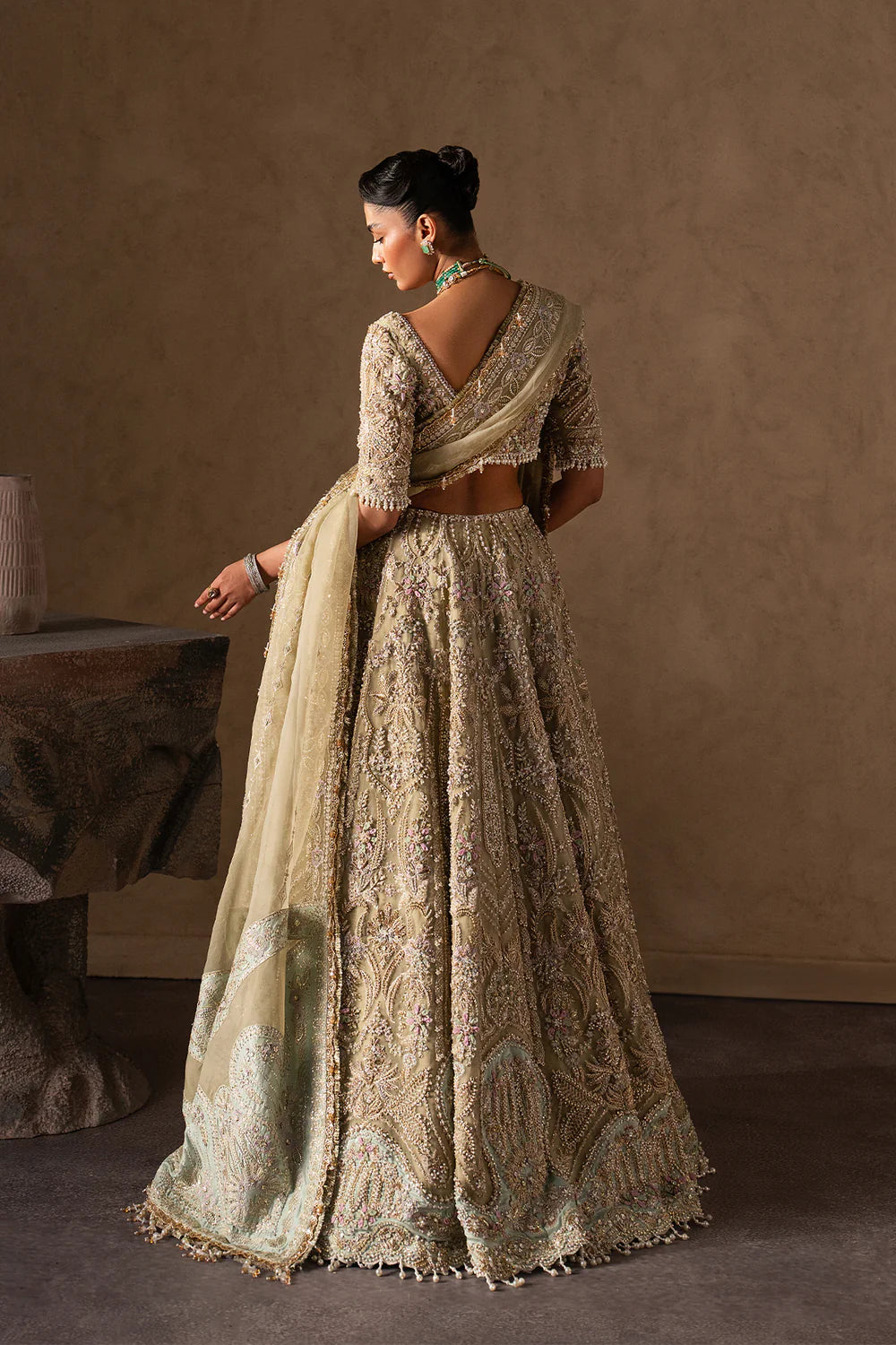 Elegant pastel gold bridal lehenga with intricate hand embellishment, paisley and floral motifs. Paired with a sheer dupatta for a timeless look.