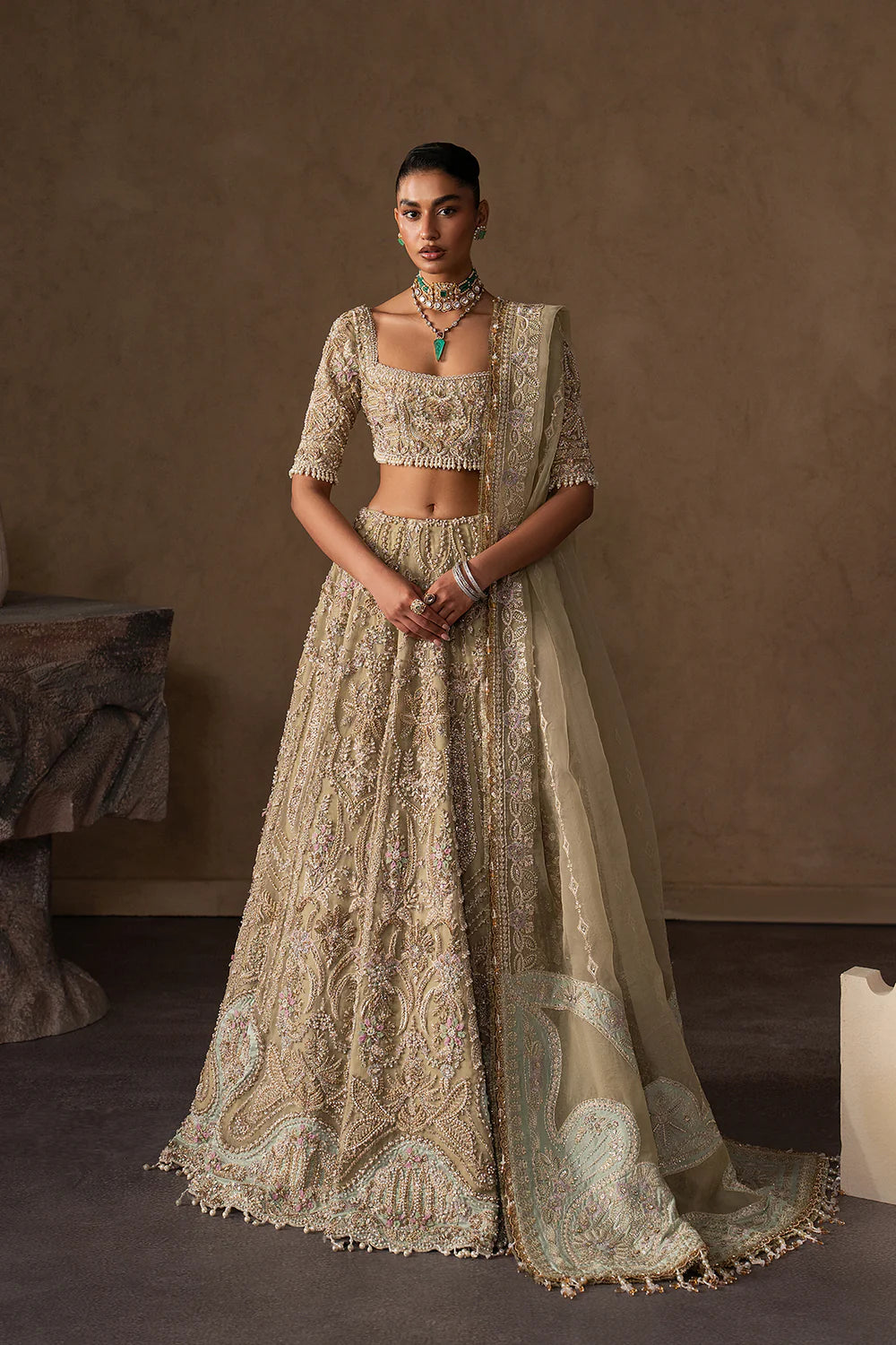 Elegant pastel gold bridal lehenga with intricate hand embellishment, paisley and floral motifs. Paired with a sheer dupatta for a timeless look.