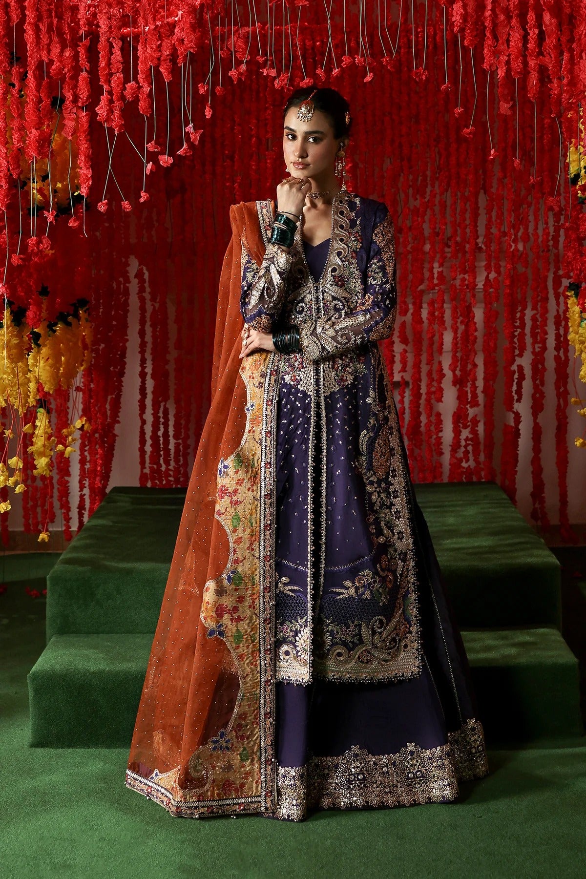 Regal purple raw silk dress with intricate embroidery, rust organza dupatta, and printed tissue zari patches. Ideal for festive and formal occasions.