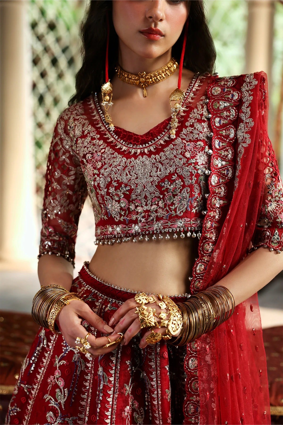 Vibrant red organza and shmoz silk embroidered panels, sleeves, dupatta, and borders paired with raw silk trousers for a bold, elegant custom outfit.